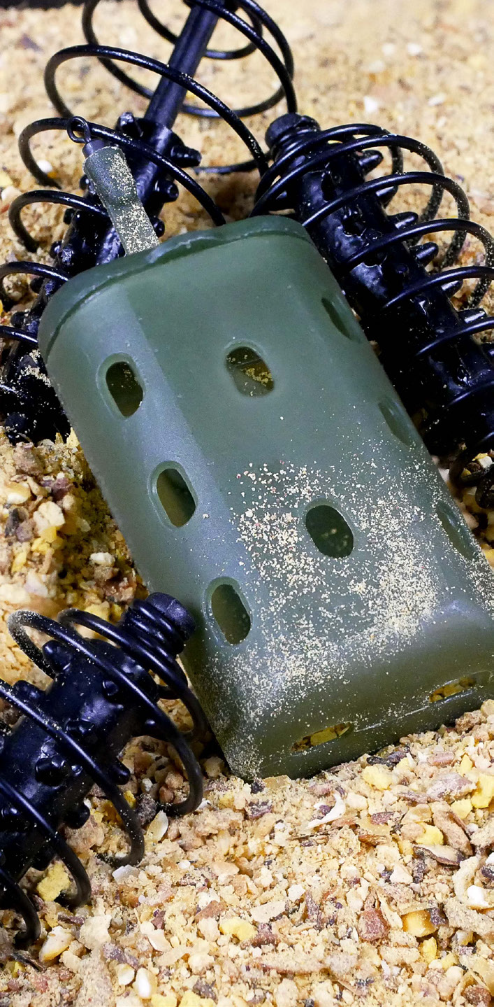 Feeder plástico rígido verde na areia com engodo - demonstração de uso em pesca de fundo