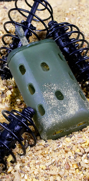 Feeder plástico rígido verde na areia com engodo - demonstração de uso em pesca de fundo